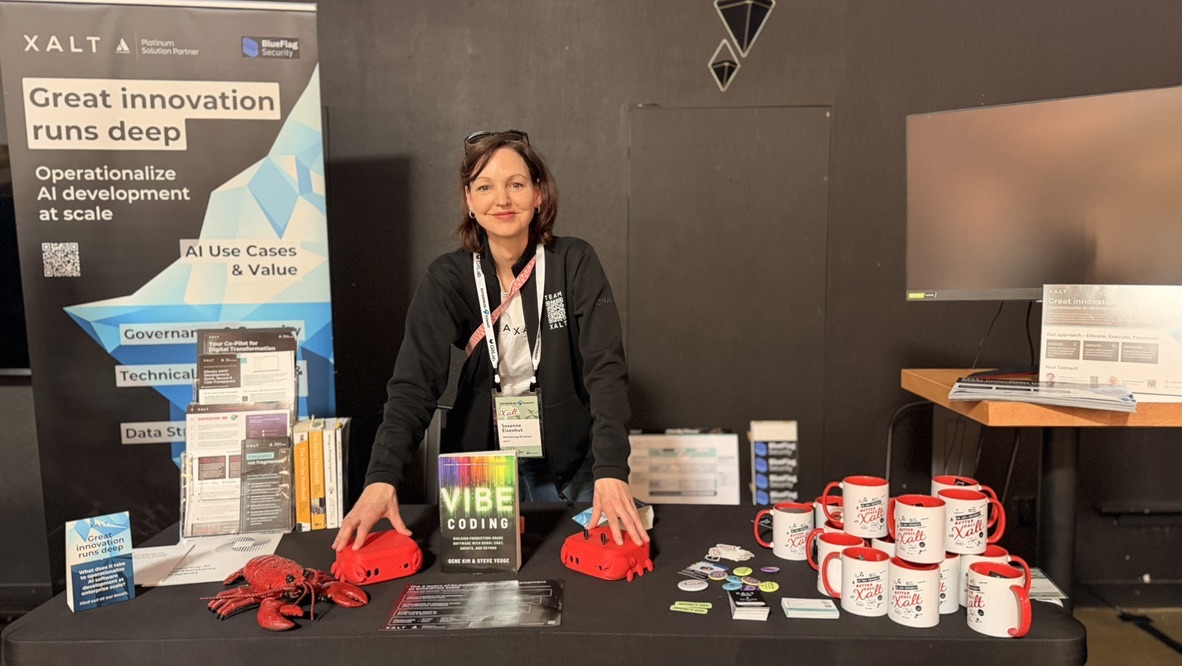 XALT team member at the XALT booth with the book “Vibe Coding” on the table